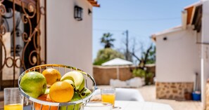 A breakfast table with a fruit bowl, glasses of orange juice, and a plate of food.