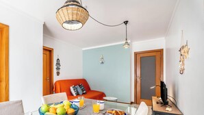 A room with a dining table, a bowl of fruit, a glass of orange juice, and a television. - #172 Falésia Beach by Home Holidays (Albufeira)