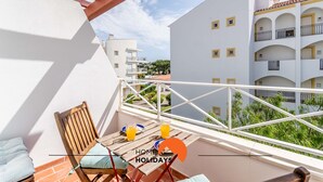 A balcony with a wooden chair, a table, and two glasses of orange juice. - #172 Falésia Beach by Home Holidays (Albufeira)