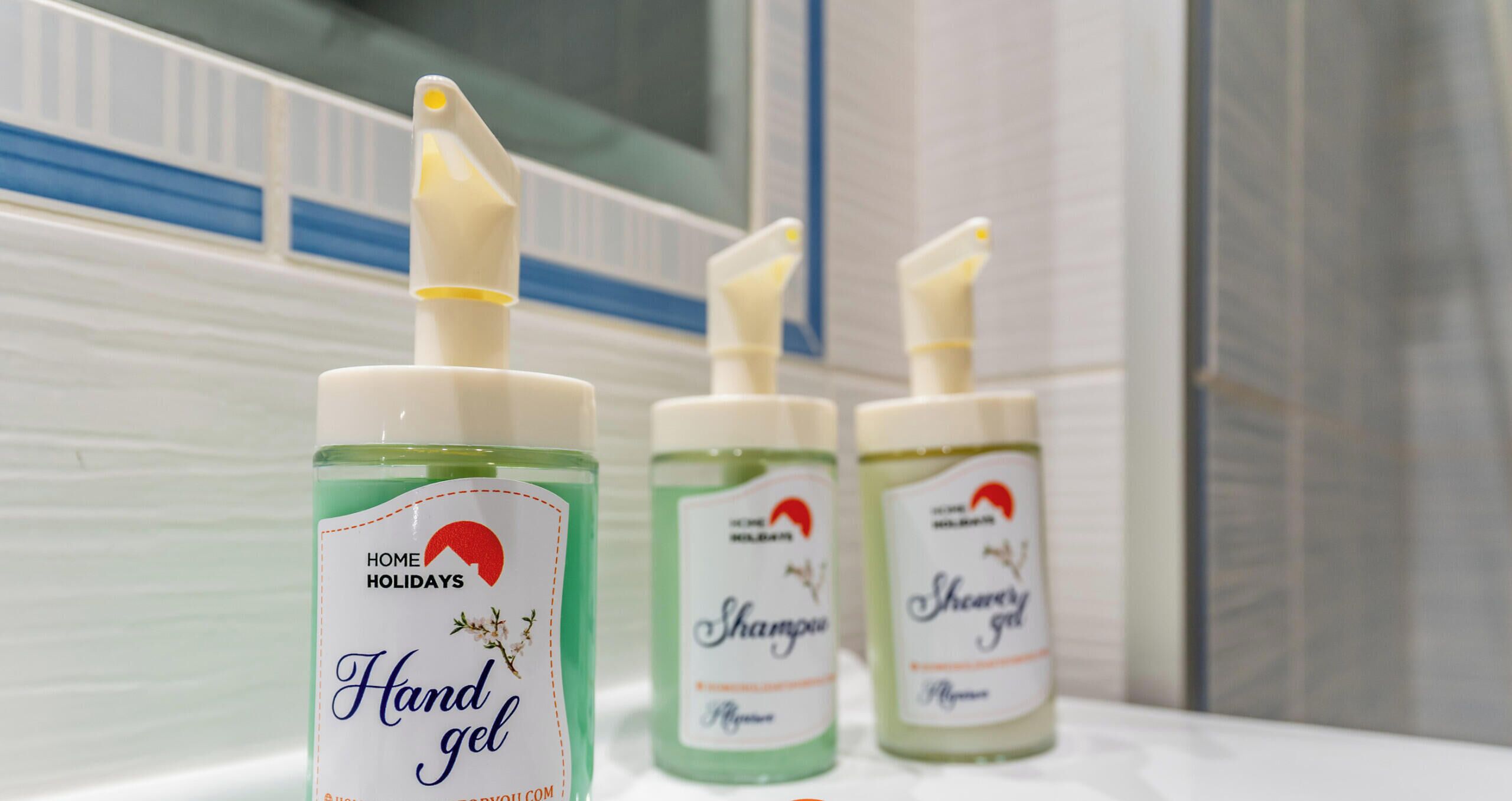 Tres botellas de gel hidroalcohólico sobre una encimera de baño.