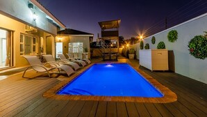 Una piscina al aire libre, sombrillas, sillones reclinables de piscina