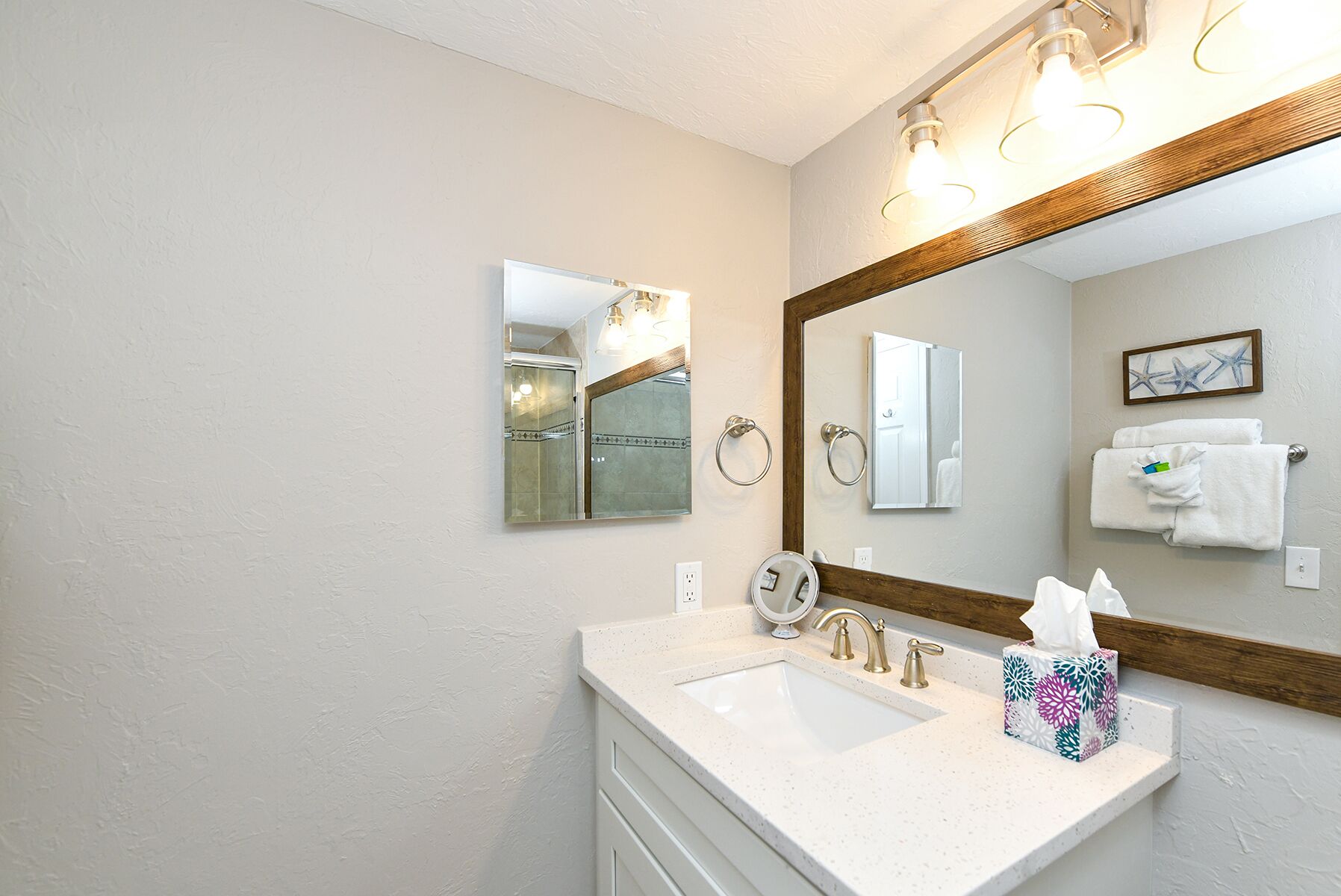 A bathroom with a large mirror, two sinks, a towel rack, and a framed picture on the wall.