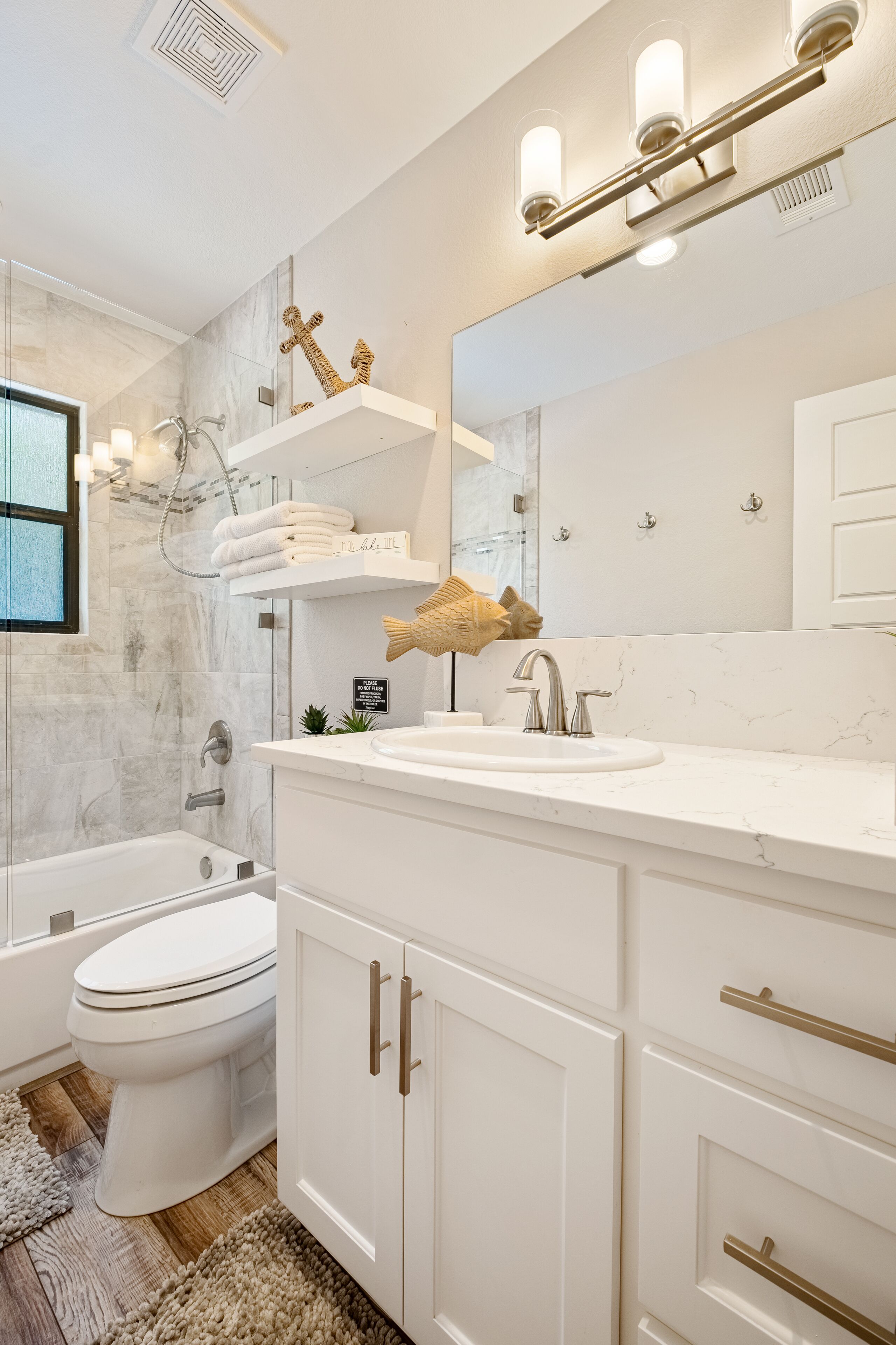 Een moderne badkamer met een bad, toilet en een wastafel met een grote spiegel en plank.