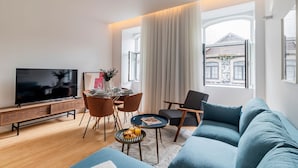 A modern living room with a TV, dining table, chairs, and a sofa. - Almada 551 - 1.1 l Stylish Getaway by LovelyStay (Porto)