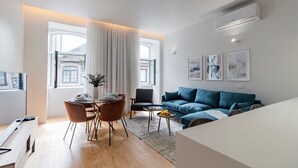 A modern living room with a dining area, a blue sofa, and a dining table set for four. - Almada 551 - 1.1 l Stylish Getaway by LovelyStay (Porto)