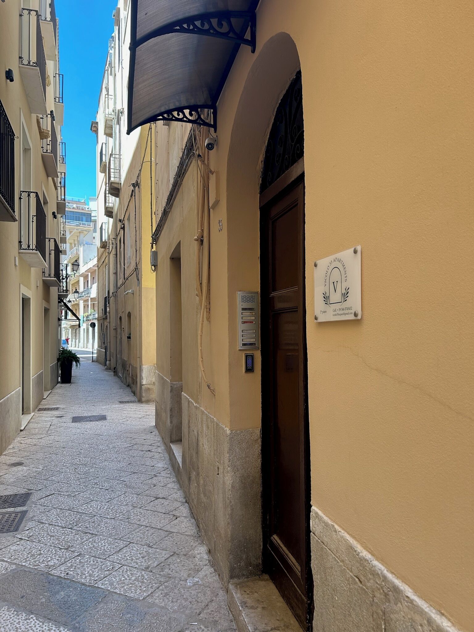 A narrow street with a building featuring a sign for 'Mercado 15 Apartments'.