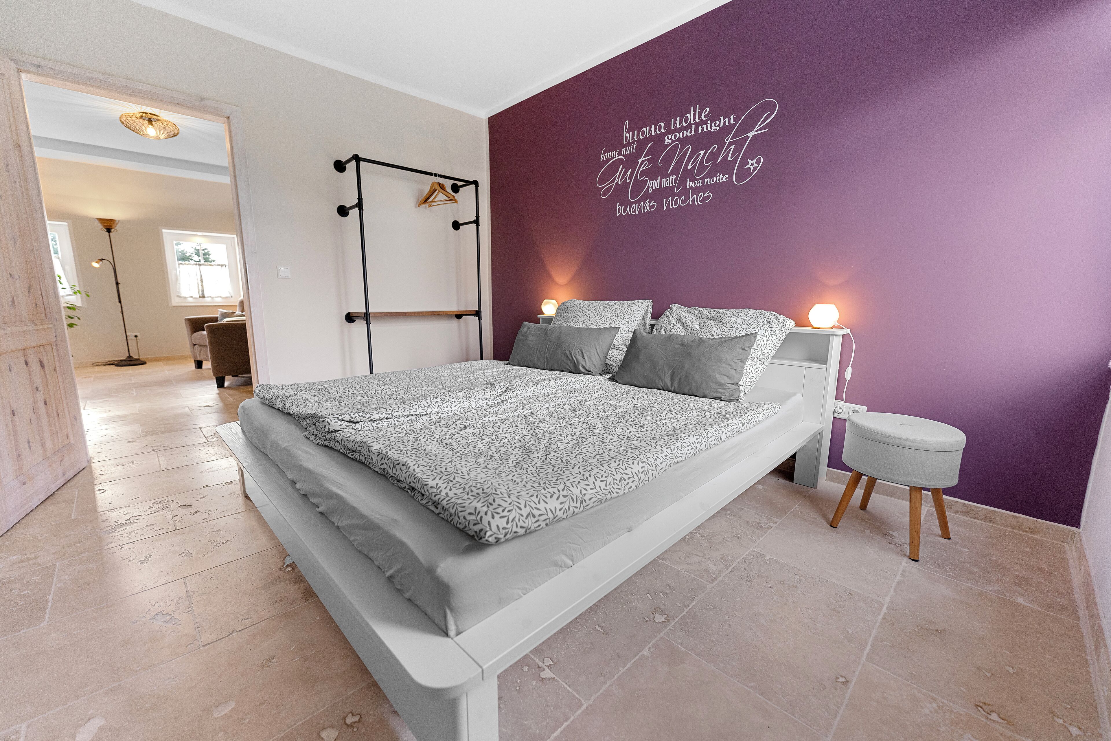 A bedroom with a bed, a nightstand, and a wall with a motivational quote.