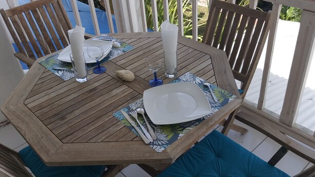 Une table de salle à manger en bois, mise avec des assiettes, des couverts et des bougies, le tout posé sur un set de table à motifs.