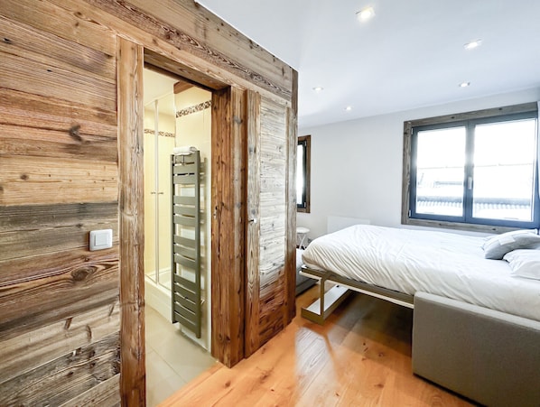 A bedroom with a wooden wardrobe, a bed, and a window with a view.