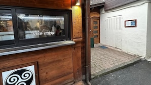 Ein Holzgebäude mit einem Fenster, das 'Take away' zeigt, und einem Schild mit der Aufschrift 'Le Suffer'.