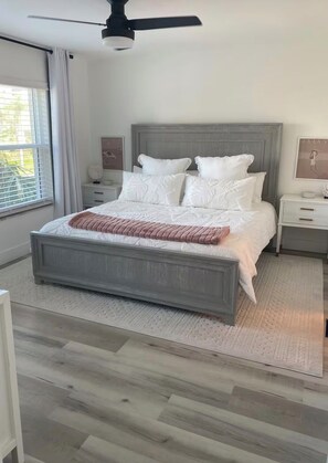 A bedroom with a bed, a ceiling fan, bedside tables, and a window with curtains. - Marco Island Getaway! Quick Walk to the Beach! (Marco island)