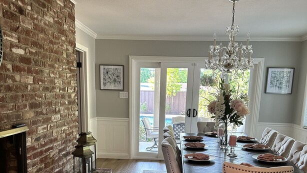 A dining area with a brick fireplace, a chandelier, and a view to the outside. - Secluded Home w/pool located 5 mins from American River  (Carmichael)