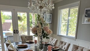 A dining room with a dark wooden table, white upholstered chairs, and a chandelier. - Secluded Home w/pool located 5 mins from American River  (Carmichael)