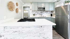 A modern kitchen with a central island, stainless steel appliances, and light blue cabinets.