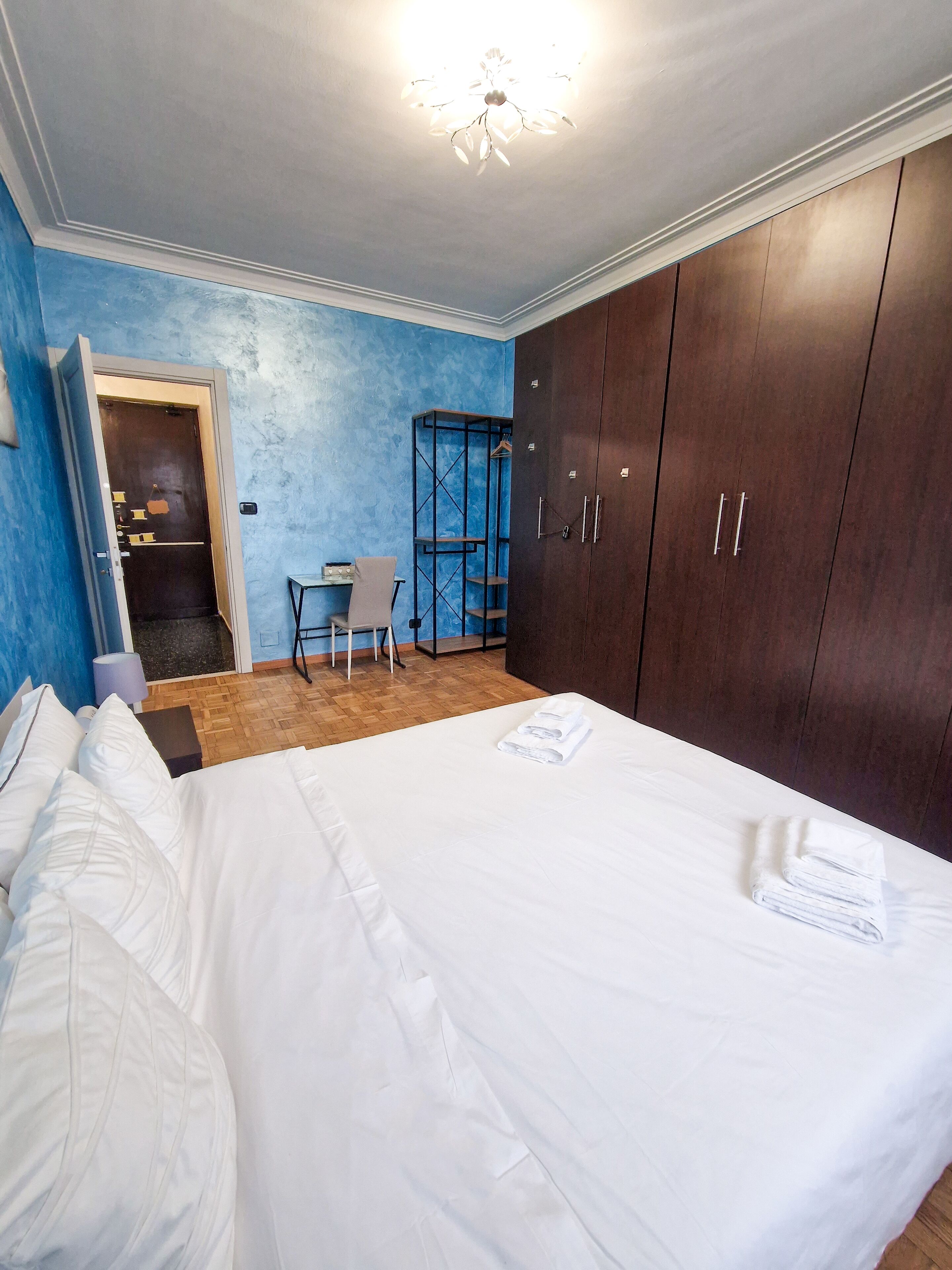 A bedroom with a bed, a desk, and a wardrobe.