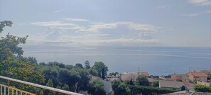 A coastal view with a clear sky, calm sea, and residential buildings. - Casa Magnolia, Vue mer et Maquis, 10 Personnes, Miomo, (Santa-Maria-di-Lota)