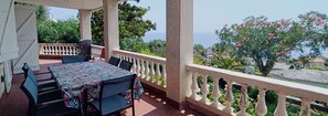 A balcony with a table and chairs, overlooking a garden and the sea. - Casa Magnolia, Vue mer et Maquis, 10 Personnes, Miomo, (Santa-Maria-di-Lota)