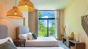 A modern bedroom with a large bed, two bedside tables, and a view of greenery through a large window.