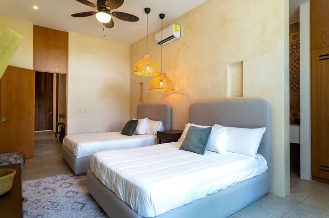 Une chambre d’hôtel avec deux lits, un ventilateur de plafond et un luminaire suspendu.