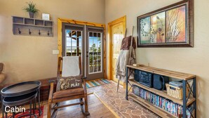 A cabin with a wooden bench, a small table, a bookshelf, and a door leading outside.