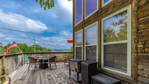 A wooden deck with outdoor furniture, a grill, and a trash bin.