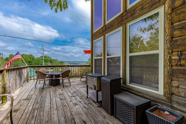 Une terrasse en bois avec des meubles d’extérieur, un barbecue et une poubelle.