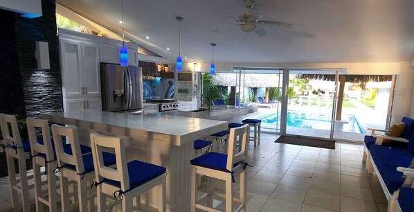 Una cocina moderna con una isla grande, asientos tipo bar y vistas a una piscina.