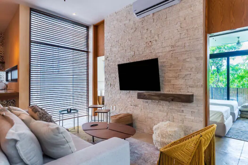 Un salon moderne avec un mur en pierre, un téléviseur fixé au mur et un canapé.