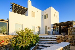 Un edificio moderno blanco con una escalera de piedra que conduce a un área cubierta.