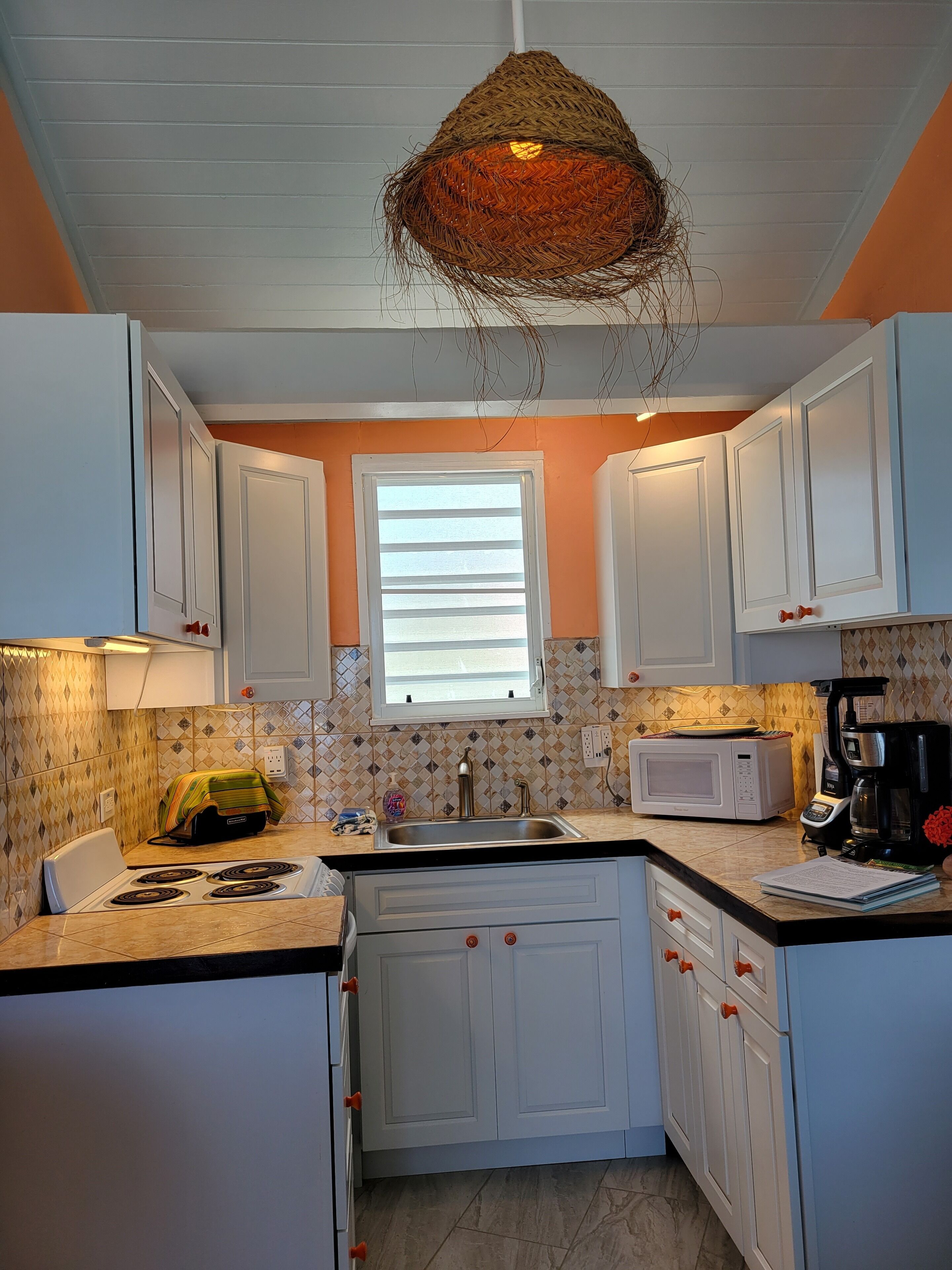 A kitchen with white cabinets, a stove, a microwave, and a coffee maker.