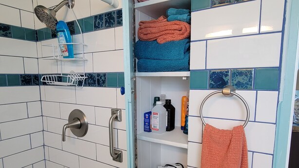 Ein Badezimmer mit Dusche, Handtuchhaltern und Ablage für Pflegeprodukte.