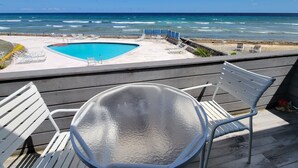 A poolside area with a glass table and white chairs, overlooking a beach and ocean. - Due to repeat guests booking directly with me, I have limited platform reviews. (Christiansted)