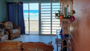 A room with wicker furniture, a ceiling fan, and a view of the beach through a sliding door. - Due to repeat guests booking directly with me, I have limited platform reviews. (Christiansted)