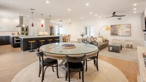 Une cuisine moderne dotée d’un îlot central, d’un coin repas avec une table en verre et d’un espace de vie comprenant un canapé et des fauteuils.