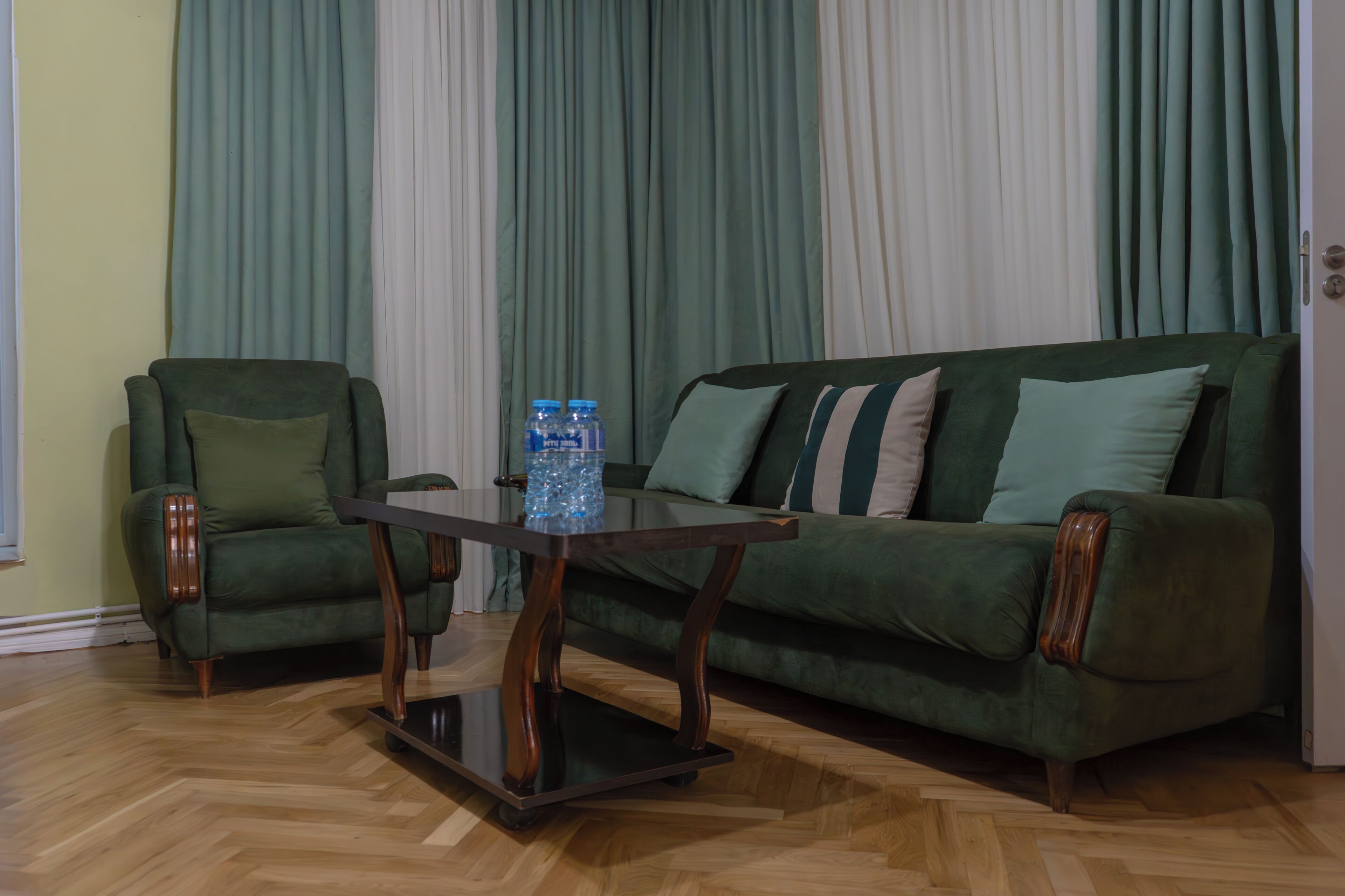 Una sala de estar con un sofá verde, un sillón a juego y una mesa de centro de madera.