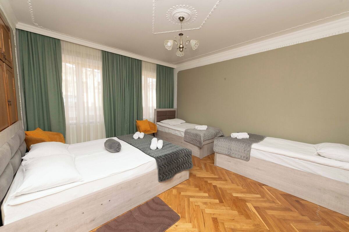 A hotel room with two beds, a wooden floor, and a chandelier.