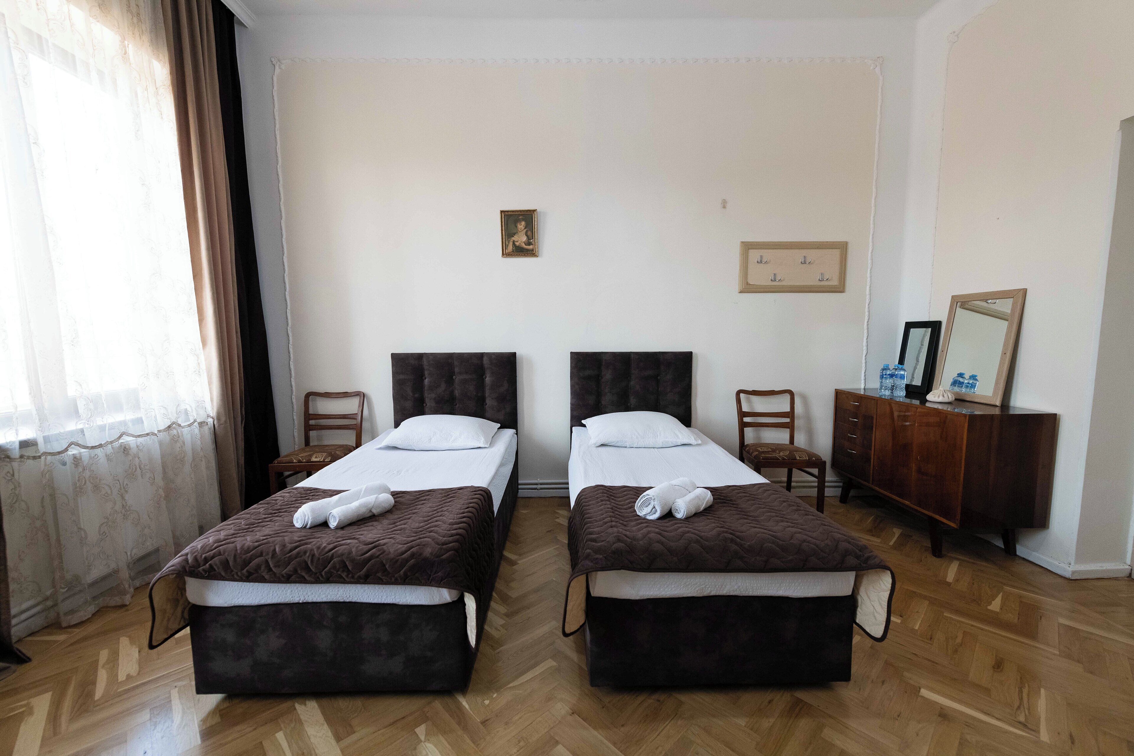 Habitación de hotel con dos camas, suelo de madera, cómoda y espejo.