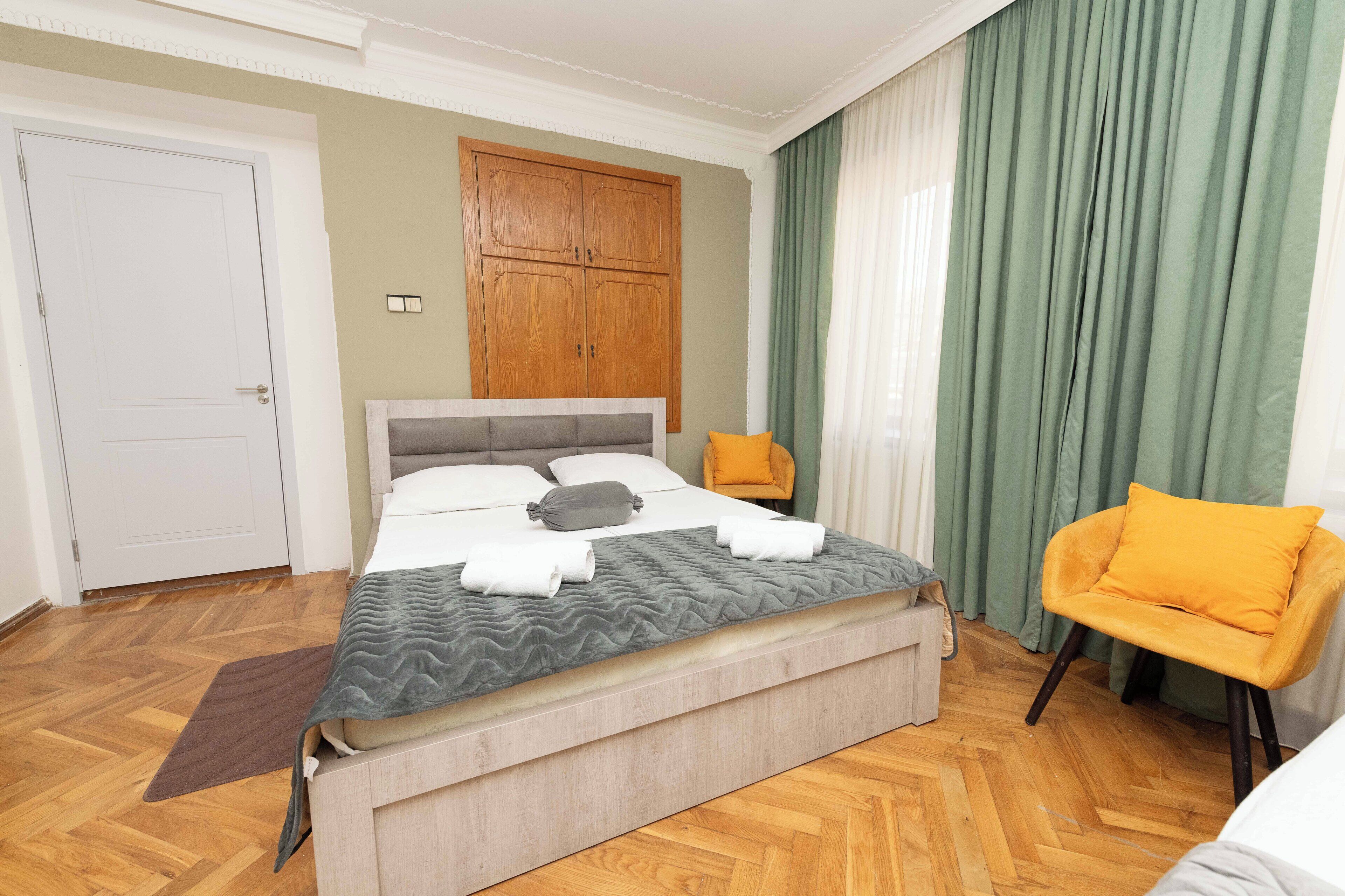 Ein Schlafzimmer mit einem Bett, einem Holzschrank, einem Stuhl und einer Tür.