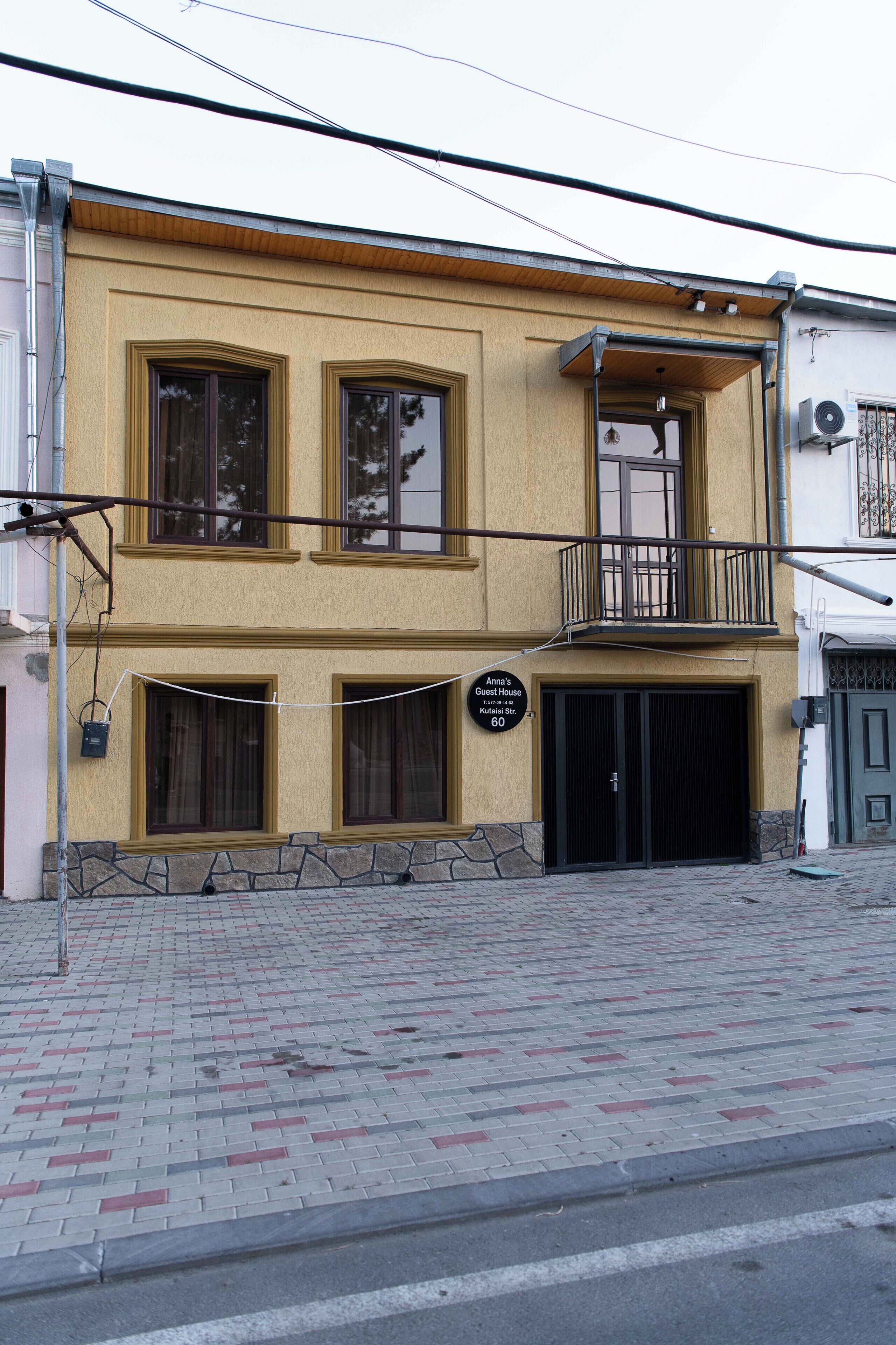 Ein zweistöckiges Gebäude mit einem Balkon im zweiten Stock, einem Schild mit der Aufschrift 'Anna's Guest House' und einem steinernen Fundament.