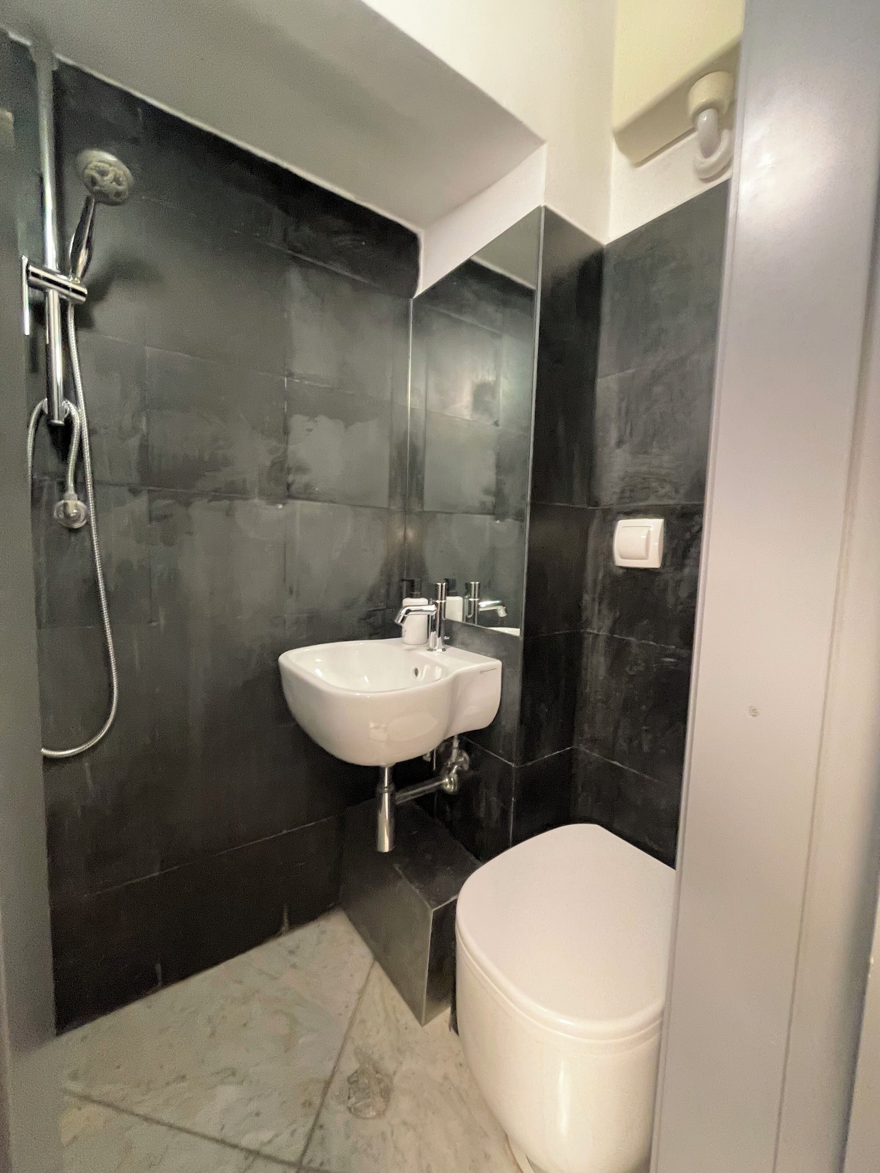 A modern bathroom with a white sink, a toilet, and a shower.