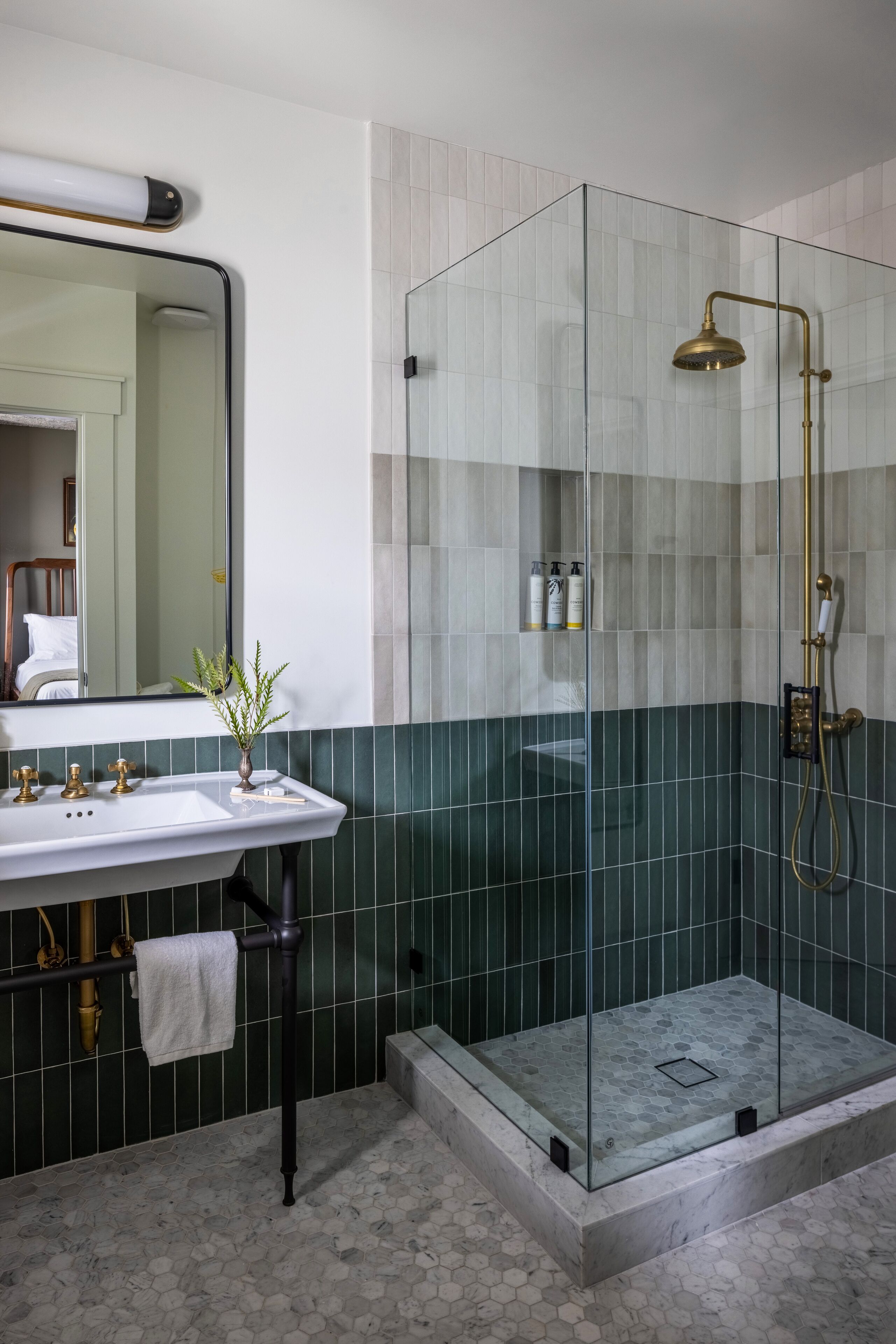 Een badkamer met een douche met glazen wand, een wastafel met handdoek en een spiegel.