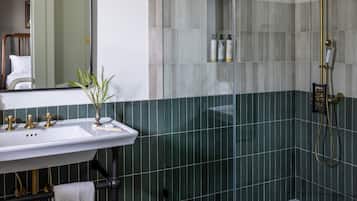 Een badkamer met een douche met glazen wand, een wastafel met handdoek en een spiegel.
