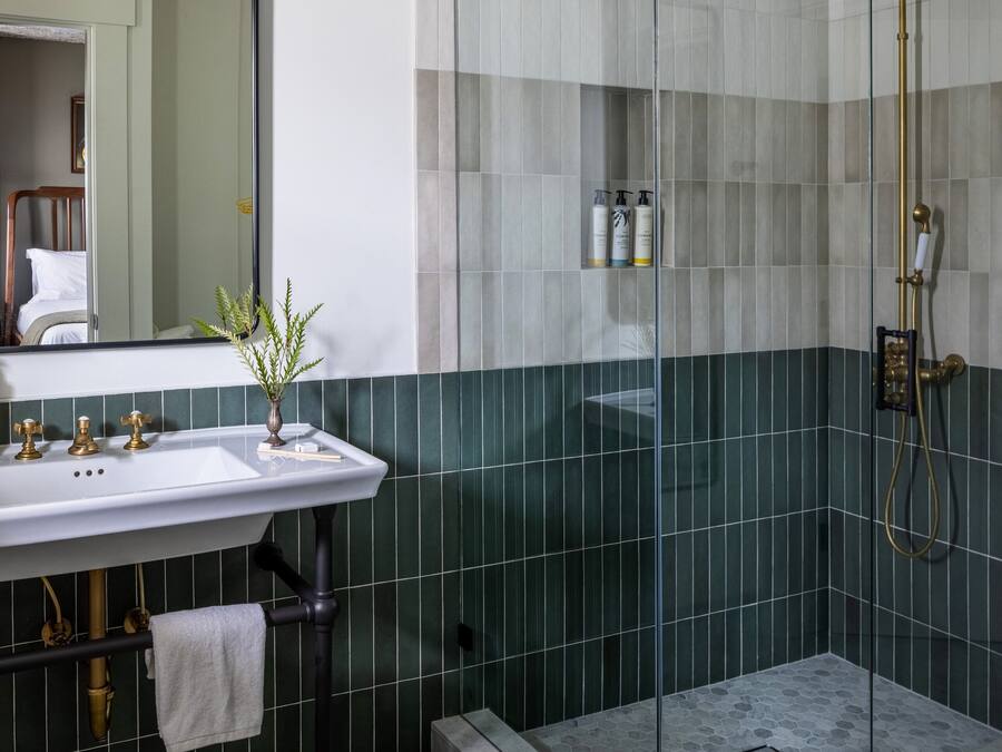 Een badkamer met een douche met glazen wand, een wastafel met handdoek en een spiegel.