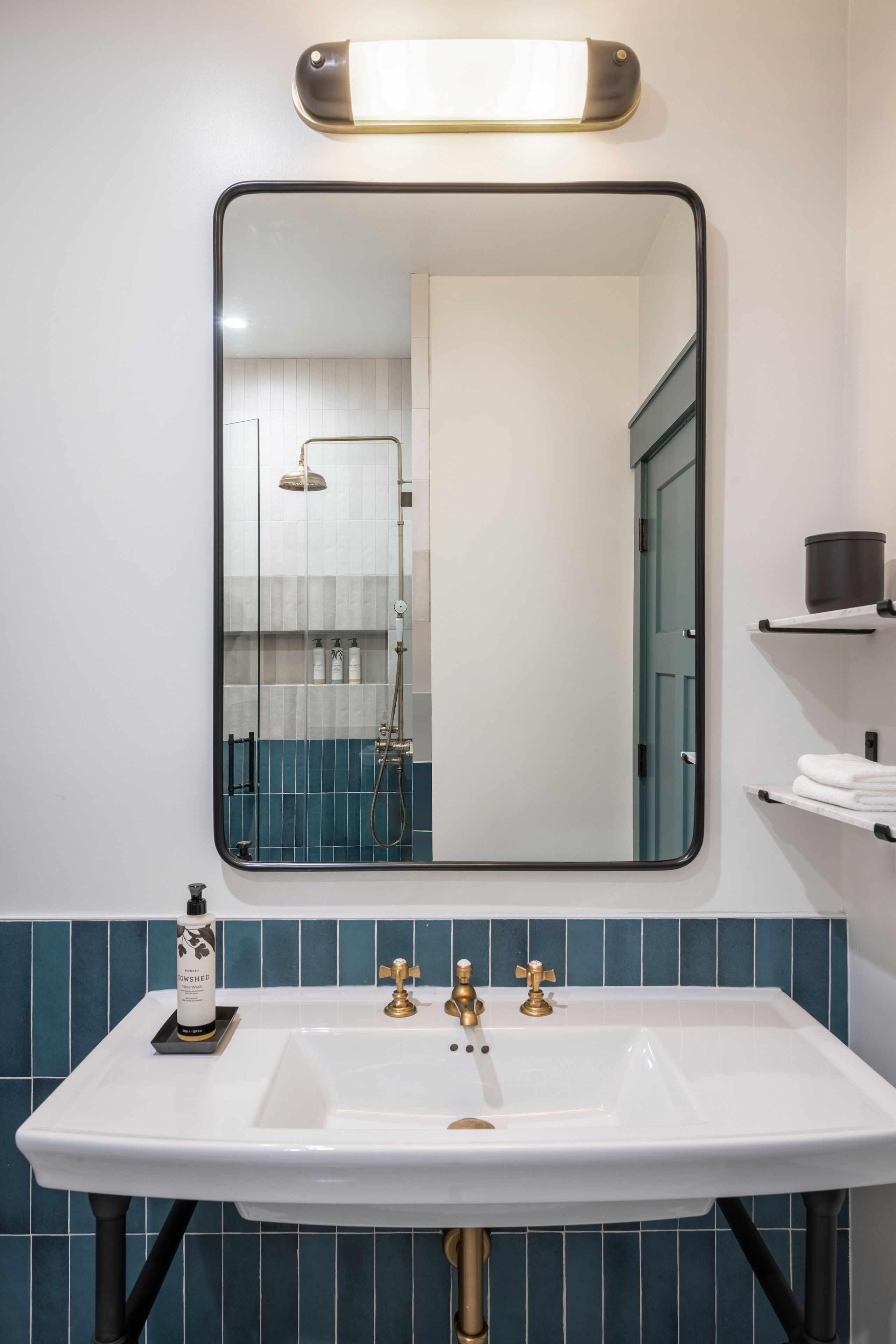 Une salle de bain avec un lavabo blanc, des robinets dorés, un miroir et une douche.
