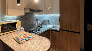 A modern kitchen with a granite countertop, stainless steel appliances, and wooden cabinets. - Great Apartment Marrakesh Gueliz (Marrakesh)