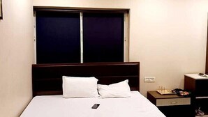 A hotel room with a bed, a nightstand, and a window with blinds. - Hotel HMS Palace (Golmuri)