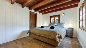 Une chambre avec un lit en bois, des murs blancs et un plafond en bois.