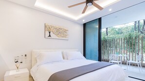 Quarto moderno com uma cama grande, ventilador de teto, mesa de cabeceira e vista para o exterior através de uma porta de vidro.