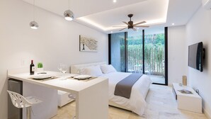 Quarto moderno com cama, escrivaninha e área de refeições.