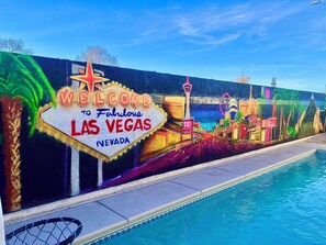 Experience the iconic 'Welcome to Fabulous Las Vegas' sign in vibrant colors, situated near a refreshing swimming pool.